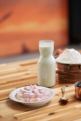 A wooden table presents the ingredients for baking traditional Cozonac. Flour, milk, and Turkish Delight sit ready for mixing. Time for some baking magic in the kitchen