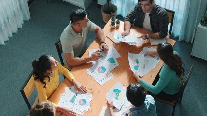 Top down view of start up business team holding paper while discussing about financial idea. Aerial view of smart diverse people brainstorming idea while looking at stock market statistic. Symposium.