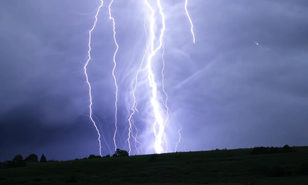 Intense lightning bolts strike against a dark night sky, illuminating the landscape with bright flashes. This dramatic moment captures the raw power and beauty of a thunderstorm during a powerful stor