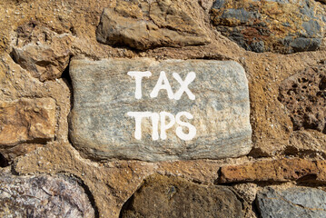 Tax tips symbol. Concept word Tax tips on beautiful grey stone on stone wall. Beautiful stone wall background. Business tax tips concept. Copy space.