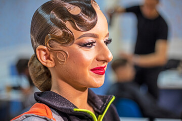 stylist photographs her makeup look on a young dancer before a competition at a salon.
