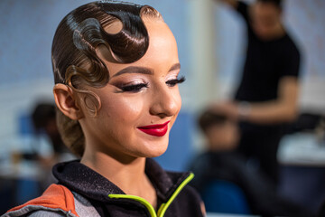 stylist photographs her makeup look on a young dancer before a competition at a salon.