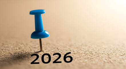 Year 2026 goal setting concept. Blue pushpin marks the date on a textured corkboard, symbolizing future planning and New Year resolutions.