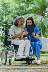 Caregiver provides assistance and support to senior in wheelchair while they engage with tablet outdoors. This moment highlights importance of care and companionship in enhancing quality of life