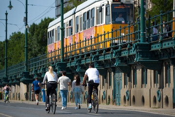Fototapeta premium People biking and walking against old tram on overpass
