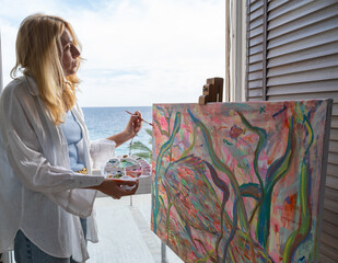 Woman painting a vibrant canvas by the seaside