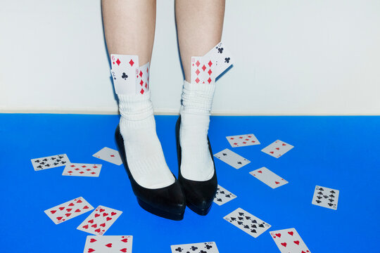 Woman in heels with playing cards on blue surface