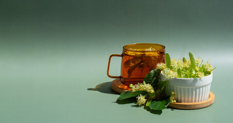Herbal linden tea with blossoms on a green background