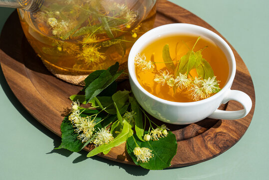 Herbal linden tea in white cup on wooden tray