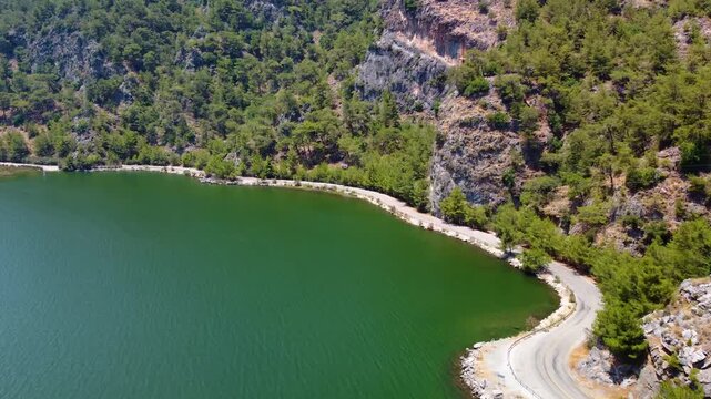 aerial drone shot capturing the serene turquoise waters of Iztuzu Beach, the winding Dalyan River Delta, and the lush green hills of Dalyan, Turkey. This iconic location is known for its natural beaut