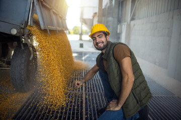 Truck unloading corn at collection point with worker