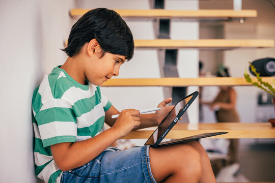 Young boy using tablet on staircase with stylus