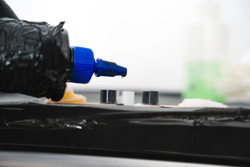 Tattoo ink bottle with blue cap dripping ink into small cups