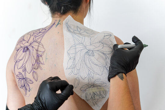 Female tattoo artist creating intricate floral design