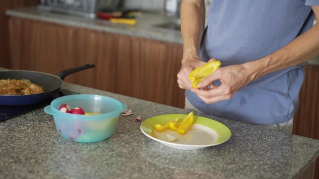 A young man is cooking food in the kitchen, focusing on preparing a delicious homemade meal. A relatable and warm moment of homemaking, creativity, and culinary enjoyment in a cozy setting.