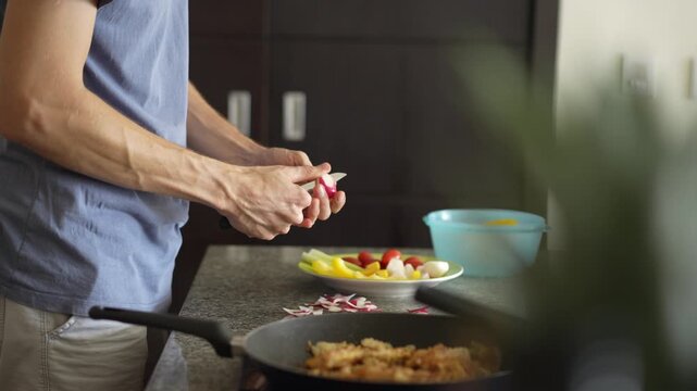 A young man is cooking food in the kitchen, focusing on preparing a delicious homemade meal. A relatable and warm moment of homemaking, creativity, and culinary enjoyment in a cozy setting.