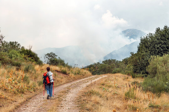 Woman hiking toward smoke in Somiedo Valley