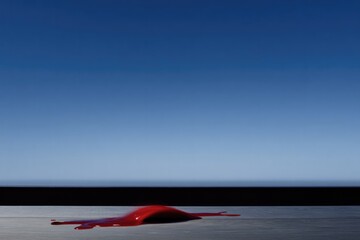 Vivid red shape contrasts starkly against expansive blue sky and