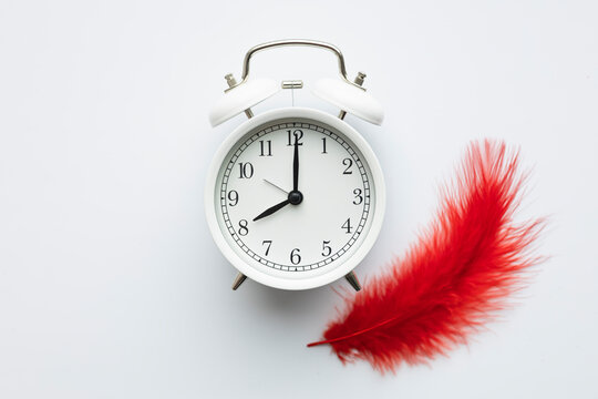 Clock and red feather illustrating menstruation concept