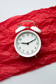Alarm clock on red paper symbolizing menstruation cycle