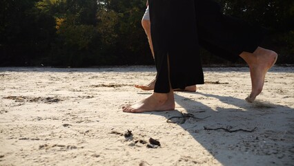 Male and female legs of pair walking on sandy beach. Bare feet of couple stepping along sand shore at sunny day. Lovers spending time together at resort. Concept of summer vacation or holiday