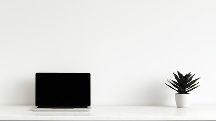 Obraz premium A laptop on a white desk with a potted plant
