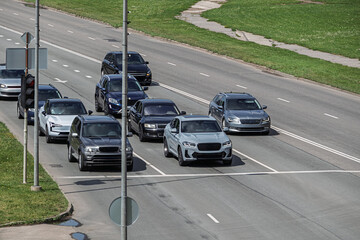 Many cars stopped at an intersection at a red traffic light. Front view of cars on the road