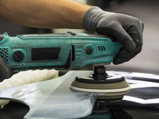 A man polishes the glass of a car with a polishing machine from small scratches with a large one. Auto glass repair, replacement. Car detailing. Hands with an orbital polishing machine. Close-up.