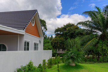 House with a white roof and a brown trim sits in front of a lush green yard