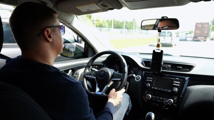 Confident man in sunglasses looking concentrated to urban road while riding automobile. Serious male driver driving a motor car at town. Guy operating the auto at highway. Slow motion