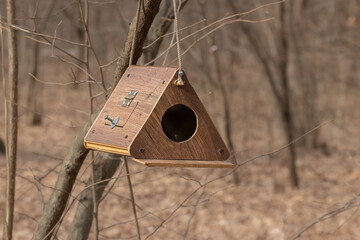 Wooden birdhouse hanging from a tree branch in forest environment.Wooden homemade bird house.