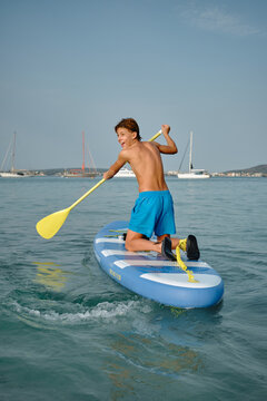 Boy enjoying paddleboarding on sunny beach day