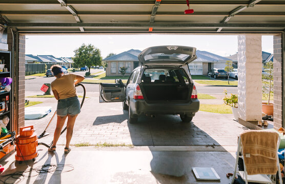 Woman cleaning car in suburban Australian neighborhood