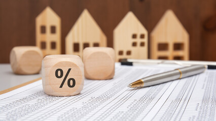 wooden cube with percent sign in front of wooden houses