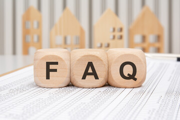 Wooden cubes with the letters FAQ on a printed document background