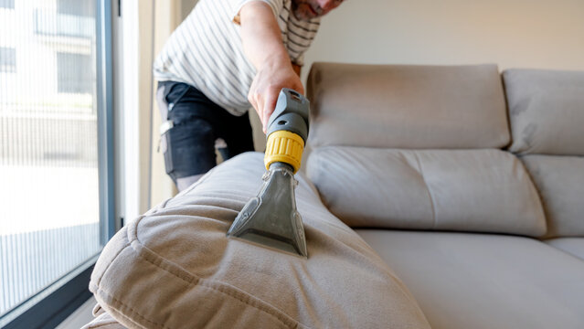 Man cleaning sofa using ionized water at home