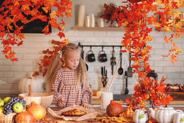 autumn still life. Happy little girl playing with dough and baking a pie in a rustic kitchen full of autumn harvest decorations, including pumpkins, fruit, and fall leaves. autumn season.