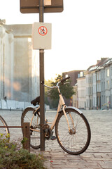 Fototapeta premium Bicycle chained to a pole with a prohibition sign in European city street at sunset.