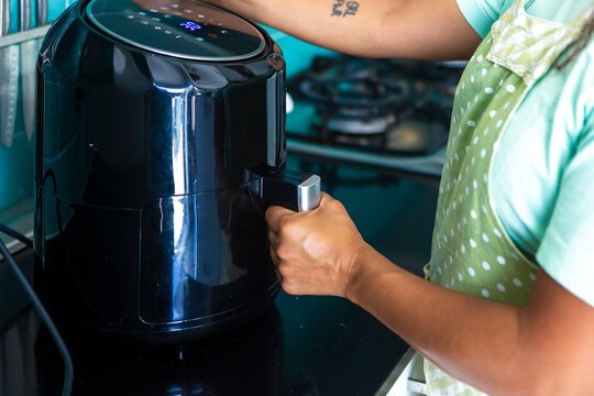 Woman using air fryer in modern kitchen