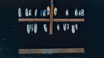 Small boats docked on a cross shaped pier, on lake Como