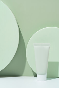 Cosmetic tube on green podium with soft shadows