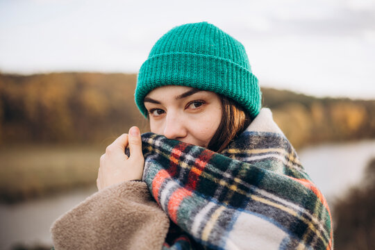 Woman wrapped in a cozy blanket during autumn walk