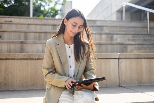 Businesswoman using tablet on outdoor steps