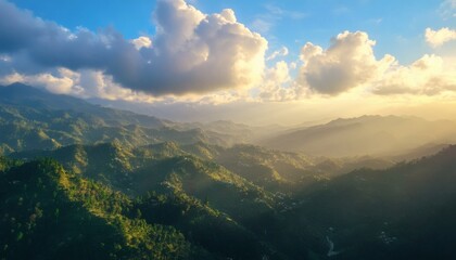 Fototapeta premium The image shows a landscape view of a mountainous region covered in green vegetation, with sunlight breaking through the clouds illuminating the scene.