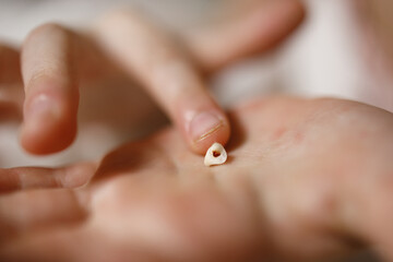 the child's fingers touch the milk tooth in the palm of the hand