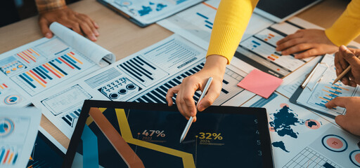 A diverse business team collaborates on financial analysis, reviewing charts and data while utilizing a tablet for insights during a strategic planning meeting in an office. SACTR