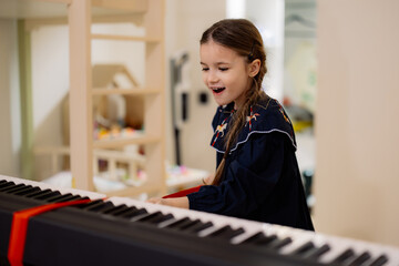 Young Girl Joyfully Playing Keyboard Indoors