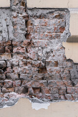 An old broken or destroyed wall with plaster and bricks. Grange background for designers. Vertical photo