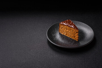 A slice of sweet layered cake covered in chocolate with nuts and caramel. A slice of chocolate cake