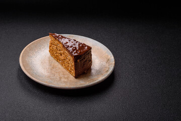 A slice of sweet layered cake covered in chocolate with nuts and caramel. A slice of chocolate cake